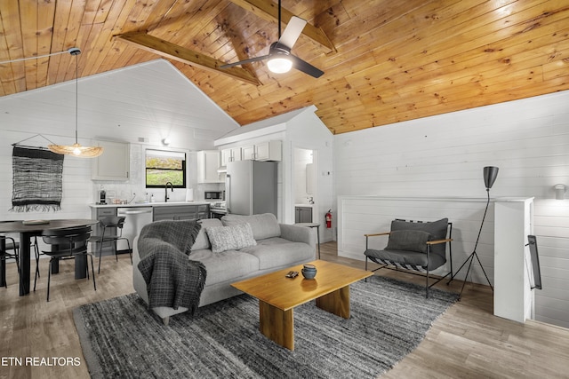 living room with light wood finished floors, wood ceiling, ceiling fan, and wood walls