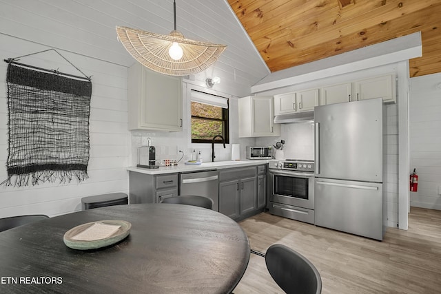 kitchen with stainless steel appliances, a sink, vaulted ceiling, gray cabinetry, and under cabinet range hood
