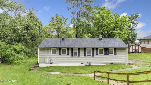 back of property with a storage shed, crawl space, a chimney, and a lawn