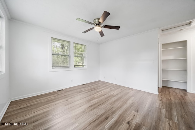 unfurnished bedroom featuring wood finished floors, ornamental molding, baseboards, ceiling fan, and a closet
