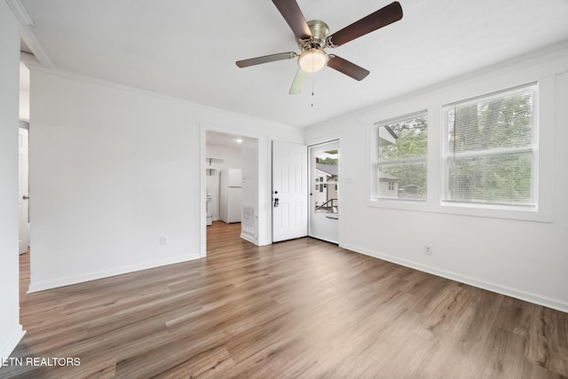 unfurnished bedroom with wood finished floors, crown molding, baseboards, and ensuite bath