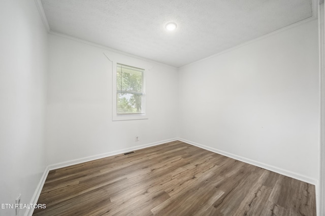 empty room featuring crown molding, wood finished floors, baseboards, and a textured ceiling