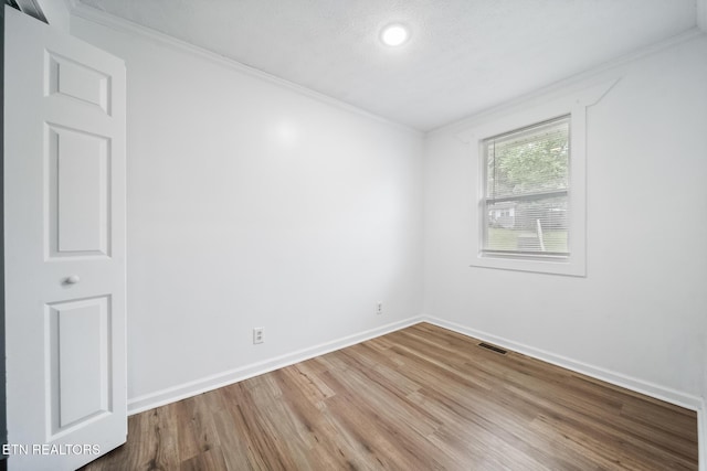 spare room with crown molding, wood finished floors, baseboards, and recessed lighting