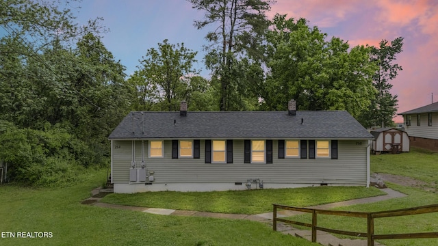 rear view of property with crawl space, a storage unit, a yard, and an outdoor structure