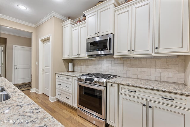 462 Chapel Grove Ln, Knoxville, TN 37934 - kitchen featuring stainless steel appliances, light wood finished floors, ornamental molding, backsplash, and light stone countertops