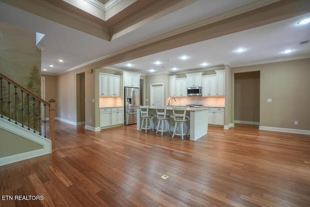 462 Chapel Grove Ln, Knoxville, TN 37934 - kitchen featuring appliances with stainless steel finishes, a kitchen bar, ornamental molding, wood finished floors, and backsplash