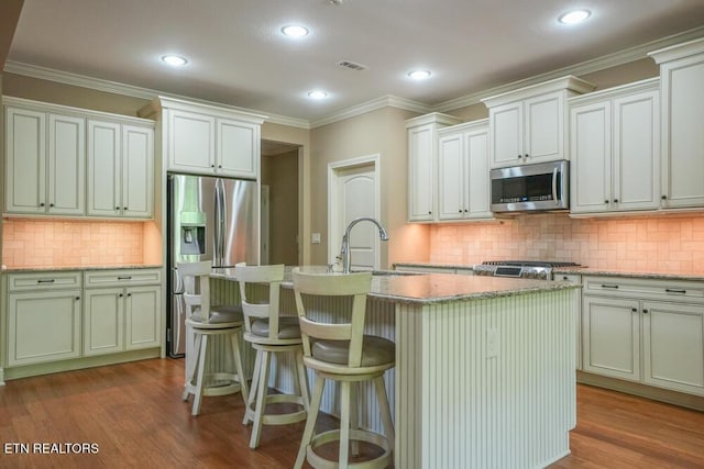 462 Chapel Grove Ln, Knoxville, TN 37934 - kitchen with stainless steel appliances, decorative backsplash, a center island with sink, wood finished floors, and crown molding