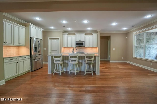 462 Chapel Grove Ln, Knoxville, TN 37934 - kitchen featuring stainless steel appliances, wood finished floors, decorative backsplash, a kitchen breakfast bar, and light countertops
