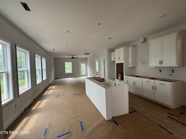 kitchen with white cabinets, a kitchen island, and ceiling fan