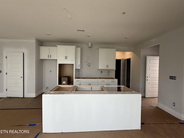 kitchen with a center island, white cabinets, and baseboards