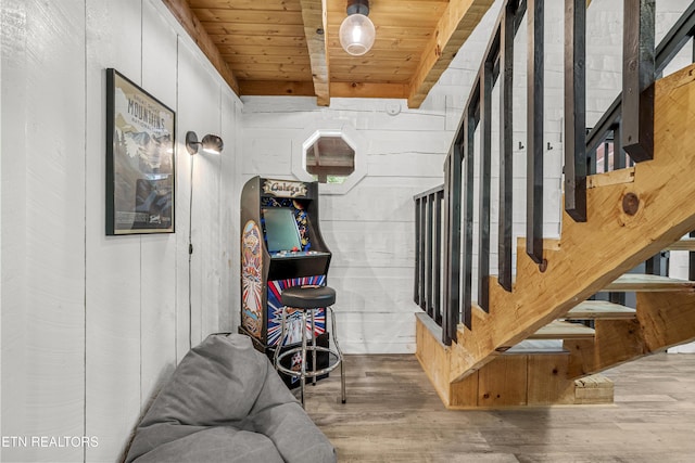 staircase with wood finished floors, beam ceiling, and wood ceiling