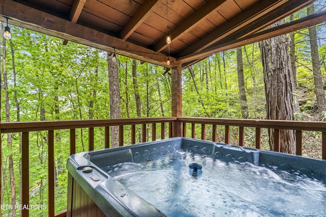 deck featuring a hot tub and a forest view