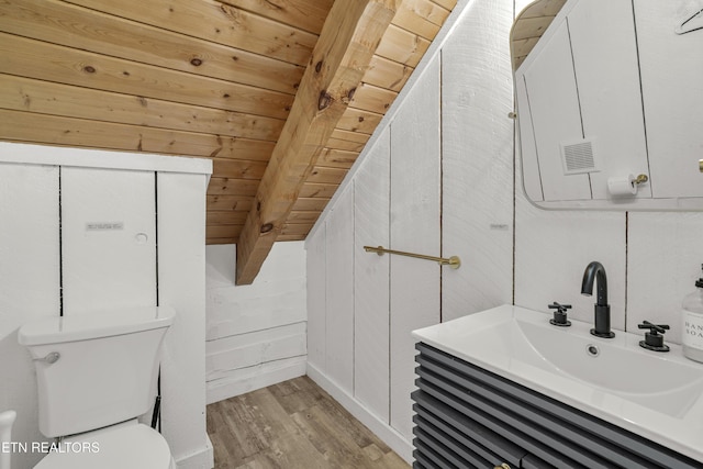 bathroom featuring wood finished floors, toilet, wooden walls, and vanity
