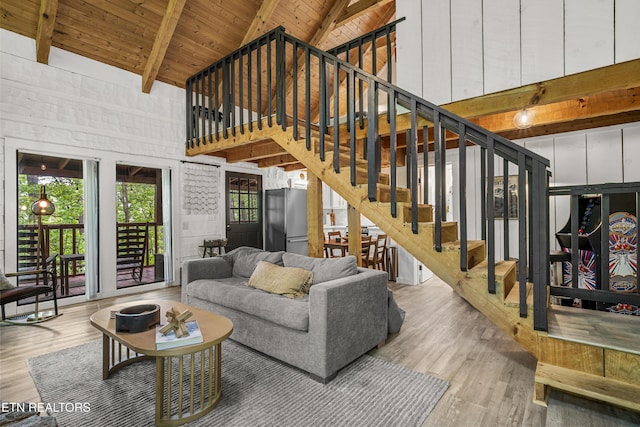 living room with beamed ceiling, wooden ceiling, wood finished floors, stairs, and high vaulted ceiling