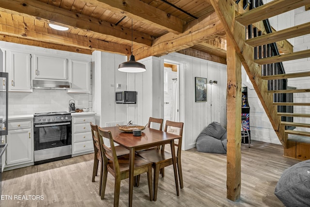 dining space featuring wooden ceiling, light wood-style floors, beamed ceiling, and stairway