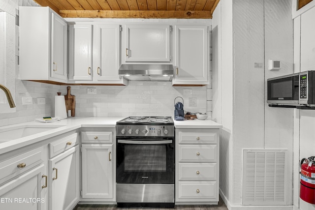 kitchen featuring appliances with stainless steel finishes, wooden ceiling, wall chimney exhaust hood, backsplash, and white cabinetry