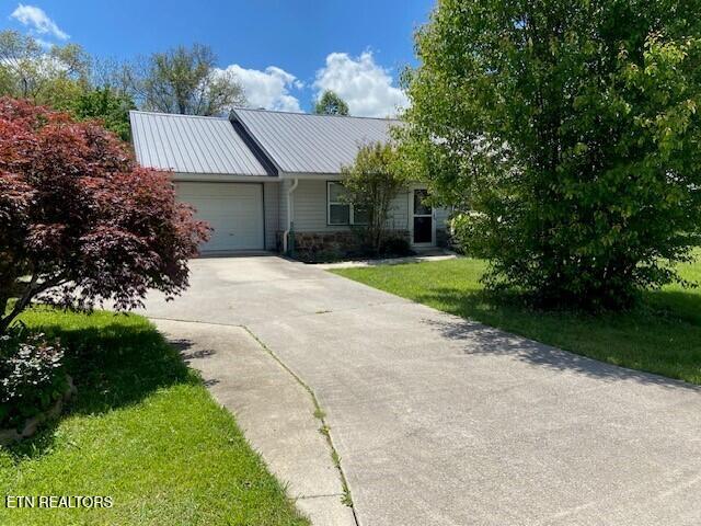 33 Wood Ln, Sparta, TN 38583 - single story home with a garage, concrete driveway, a front yard, stone siding, and metal roof