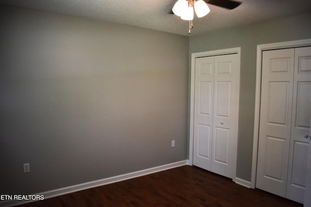 33 Wood Ln, Sparta, TN 38583 - unfurnished bedroom featuring dark wood-type flooring, baseboards, two closets, a textured ceiling, and a ceiling fan