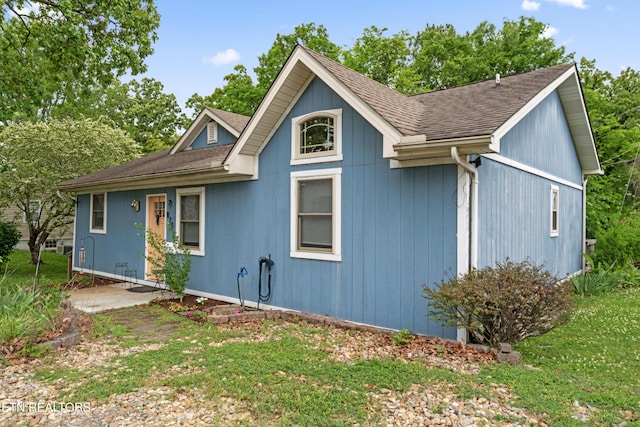 view of front of home with roof with shingles and a front yard