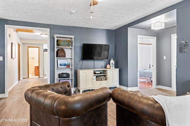 living room featuring a textured ceiling, wood finished floors, and baseboards