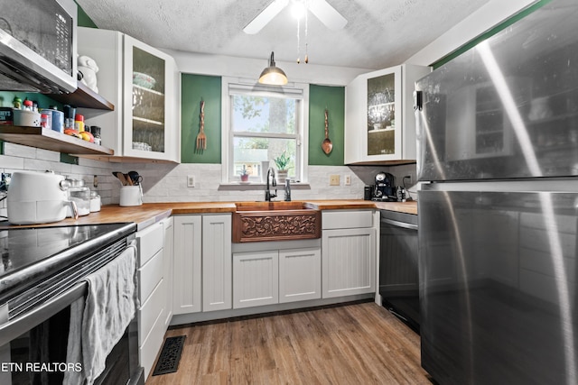 kitchen featuring freestanding refrigerator, black electric range, butcher block countertops, dishwasher, and light wood finished floors