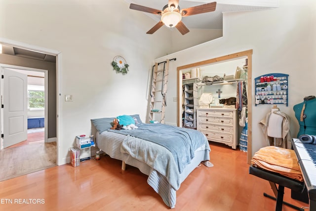 bedroom with light wood finished floors, vaulted ceiling, a closet, and ceiling fan