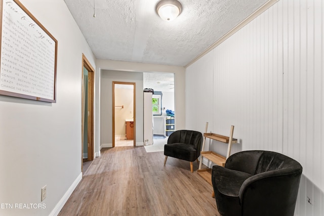 living area featuring wood finished floors, a textured ceiling, and baseboards