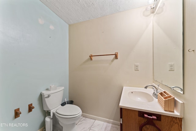 bathroom featuring a textured ceiling, marble finish flooring, baseboards, vanity, and toilet