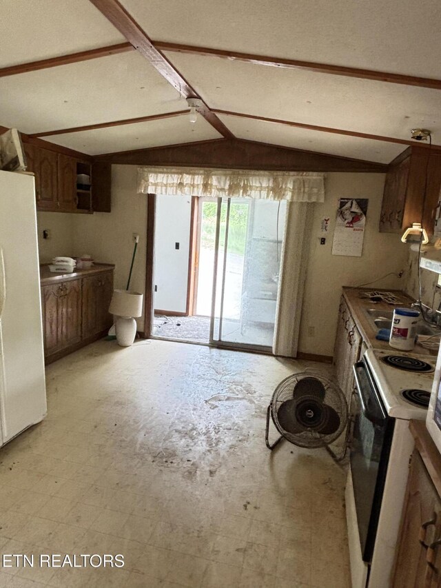 kitchen with freestanding refrigerator, electric range oven, and light countertops