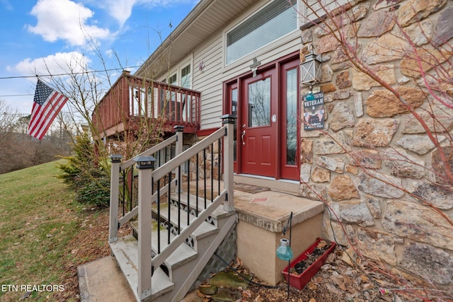property entrance with stone siding and a deck