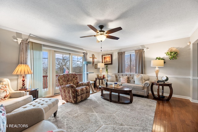 living area with a ceiling fan, plenty of natural light, hardwood / wood-style flooring, a textured ceiling, and ornamental molding