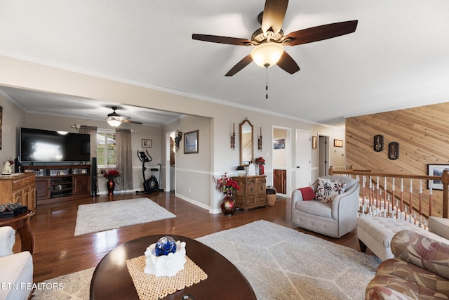 living area with ceiling fan, crown molding, wood finished floors, wood walls, and baseboards