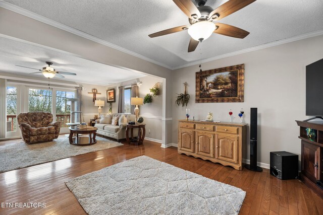 living room with ceiling fan, dark wood finished floors, a textured ceiling, baseboards, and crown molding