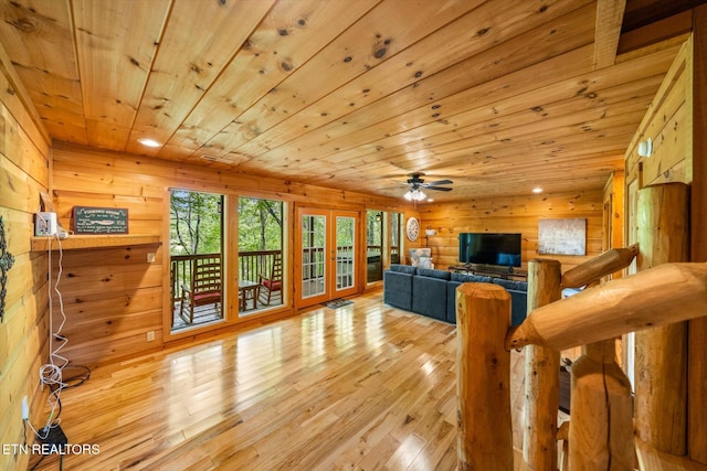 living room with french doors, wood ceiling, light wood-style floors, wood walls, and a ceiling fan