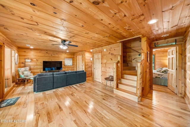 living area with wood ceiling, wood-type flooring, stairs, wood walls, and ceiling fan