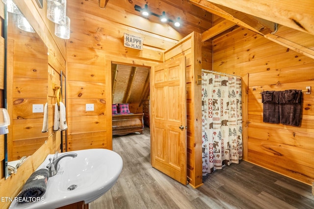 full bathroom featuring wood finished floors, wood walls, a shower with curtain, and a sink