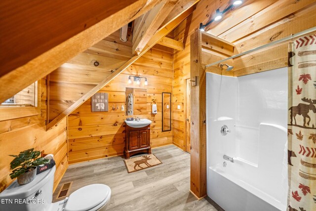 bathroom featuring toilet, wood walls, shower / bath combo, wood finished floors, and vanity