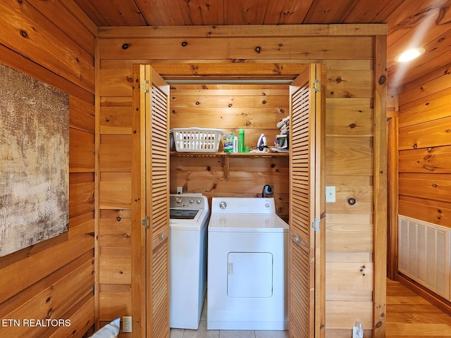 clothes washing area featuring wood walls, washer and clothes dryer, and wood ceiling