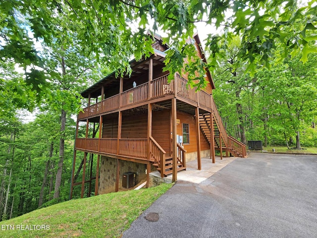 view of side of home with central AC, stairway, a deck, and stone siding