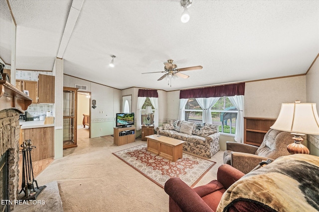 living area featuring light carpet, a fireplace, a textured ceiling, ornamental molding, and ceiling fan