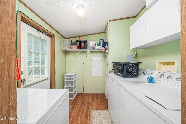 laundry room featuring cabinet space, washing machine and clothes dryer, crown molding, wood finished floors, and a textured ceiling
