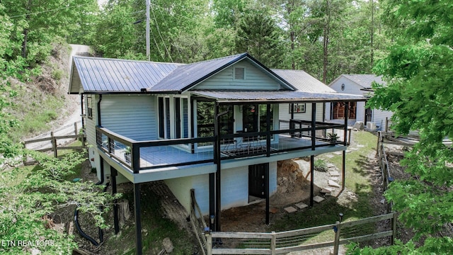 rear view of property featuring metal roof, fence, and a wooden deck