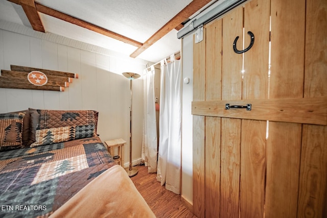 bedroom featuring light wood finished floors and beam ceiling