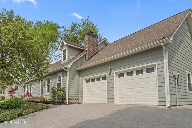 9945 Tierra Verde Dr, Knoxville, TN 37922 - view of side of home featuring driveway, a chimney, an attached garage, and a shingled roof