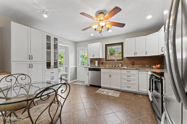 9945 Tierra Verde Dr, Knoxville, TN 37922 - kitchen with appliances with stainless steel finishes, a sink, backsplash, white cabinetry, and stone counters