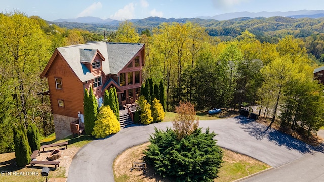 view of subject property with a heavily wooded area and a mountainous background
