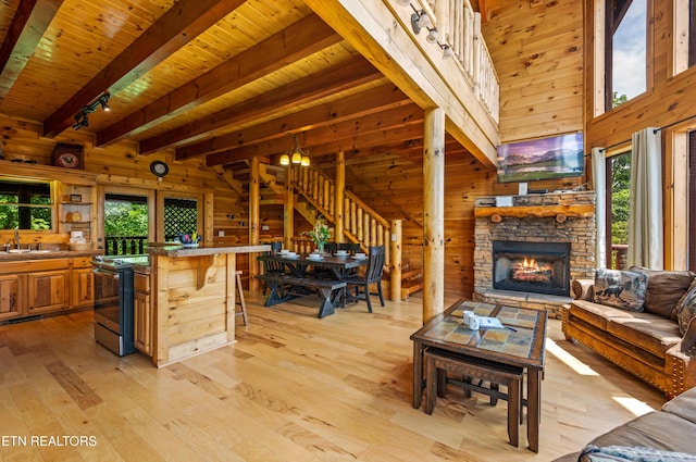 living area with wooden ceiling, stairs, wooden walls, beam ceiling, and light wood-style flooring