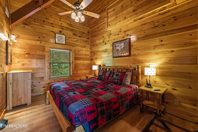 bedroom featuring light wood-style flooring, wooden walls, and beam ceiling
