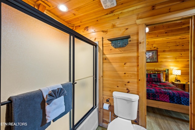 full bathroom with wood finished floors, wooden walls, shower / bath combination with glass door, toilet, and wooden ceiling