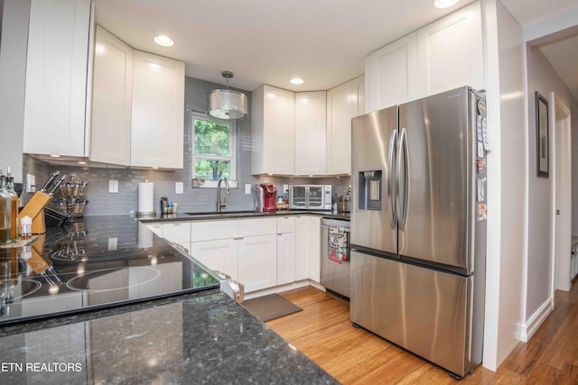 409 Celebration Rd, Knoxville, TN 37934 - kitchen with stainless steel appliances, a sink, white cabinetry, light wood-type flooring, and decorative backsplash